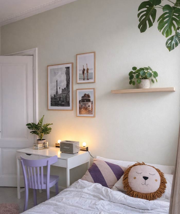 Kinderkamer met lichte groentint op de muur, houten wandplank en pannenkoekenplant boven het bed